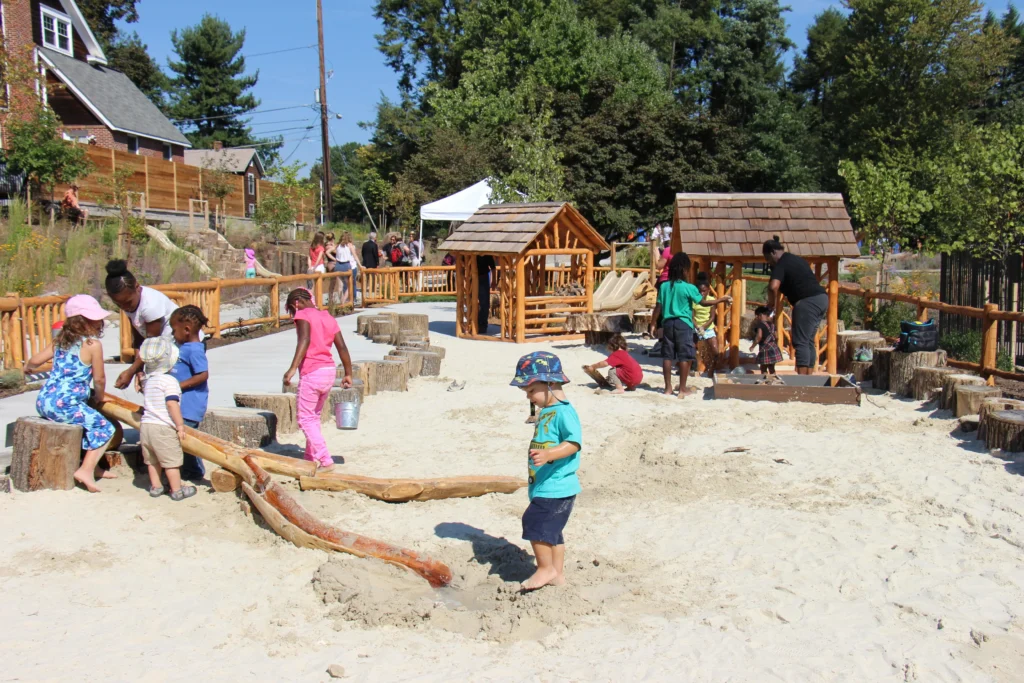 Young children playing in a preschool playground sandbox.